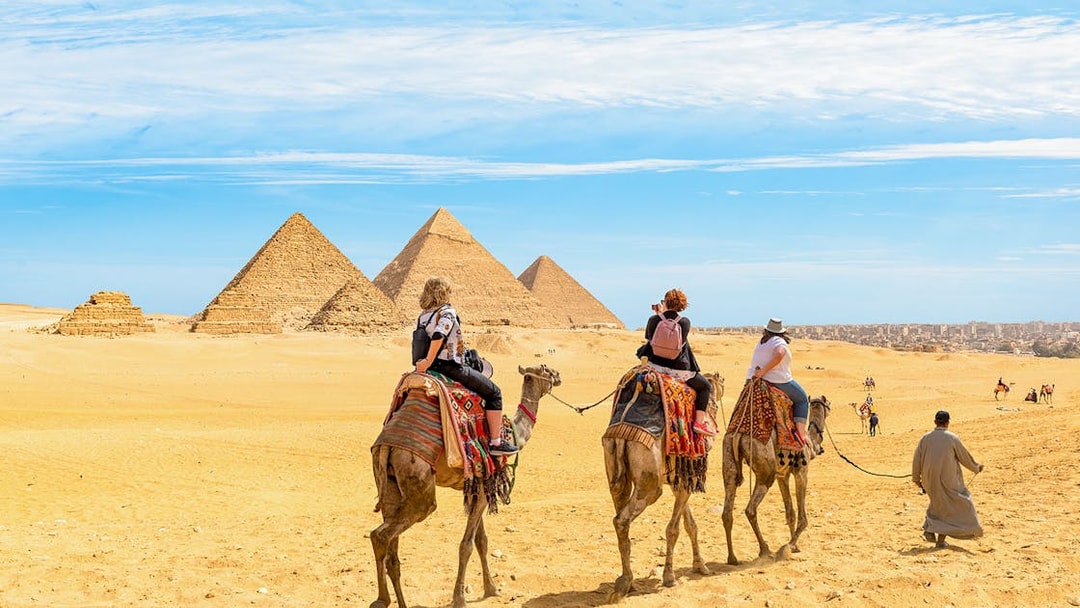 Tourists on camels approaching the Giza Pyramids in Egypt.