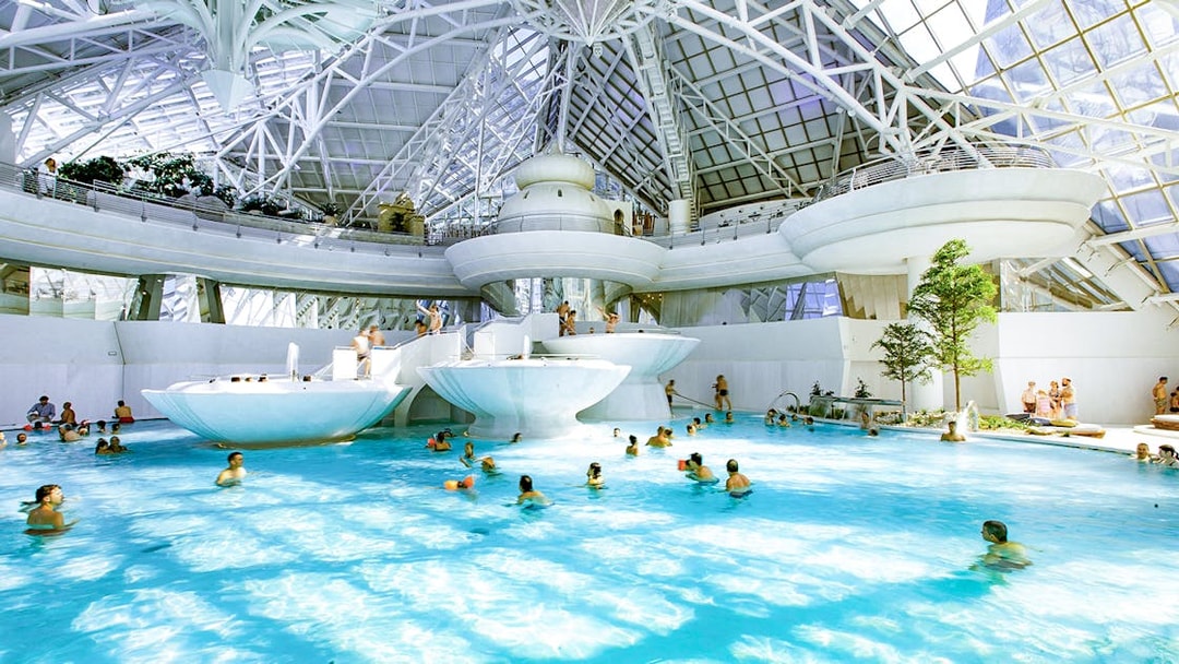 Indoor thermal pool at Caldea spa complex, Andorra, with visitors enjoying the water.