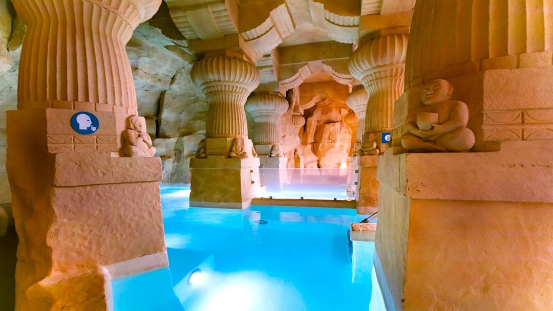 Thermal spa area with stone columns and blue water at Caldea, Andorra.