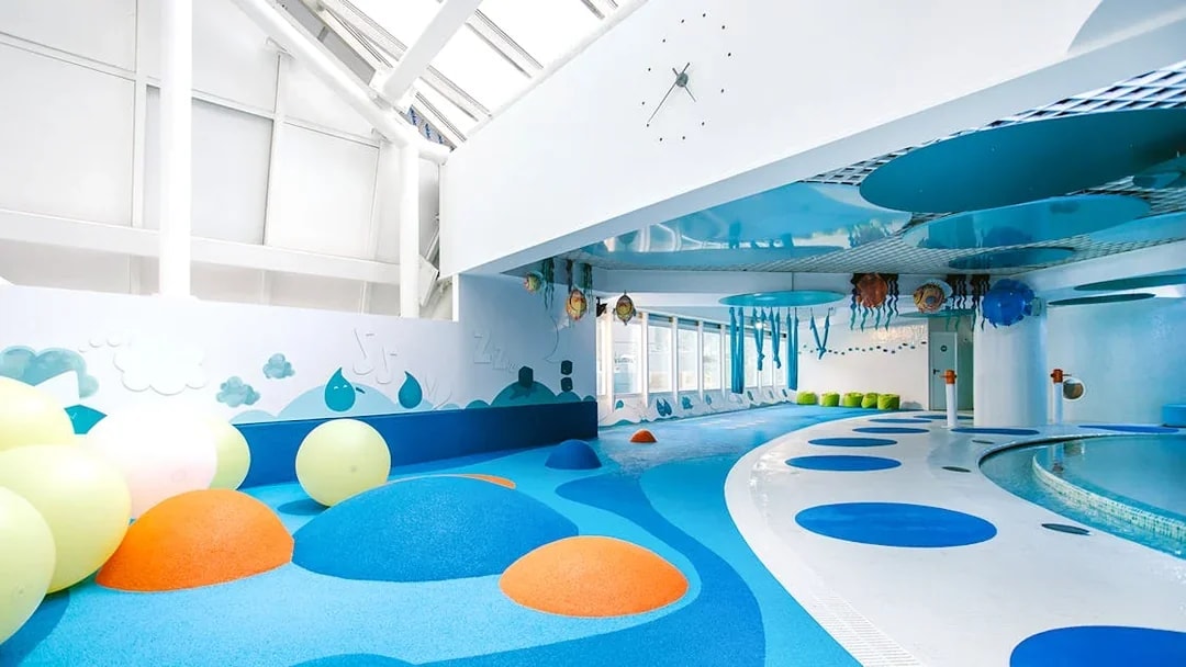 Indoor play area with colorful padded mounds and wall art at Caldea spa, Andorra.