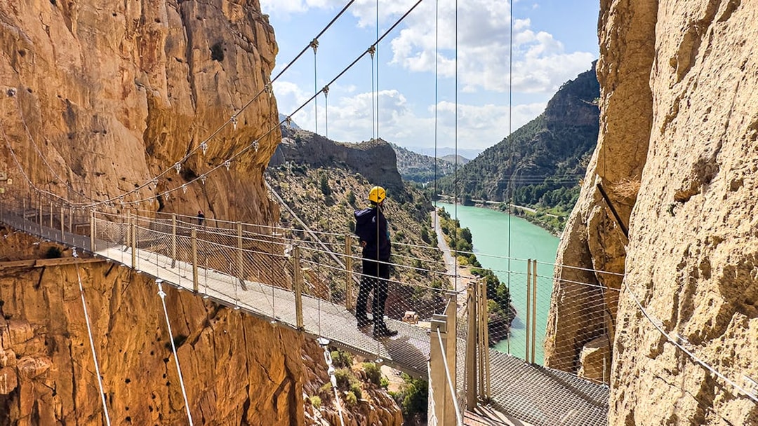 Caminito del Rey walkway with hiker overlooking river gorge in Spain.