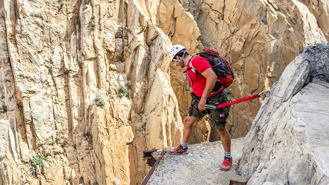 Man rappelling down Caminito del Rey in safety gear, Spain.