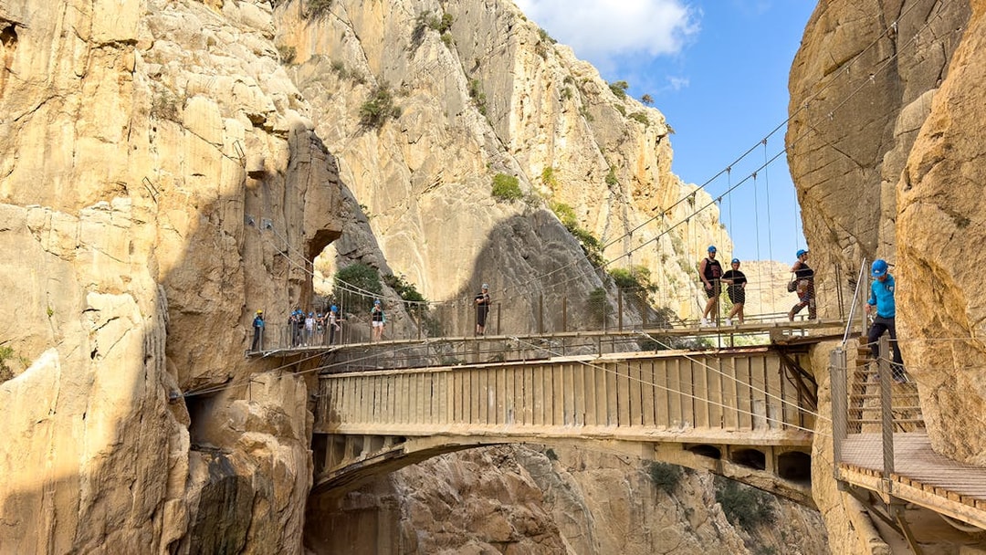 Hikers crossing suspension bridge on Caminito del Rey guided tour in Spain.