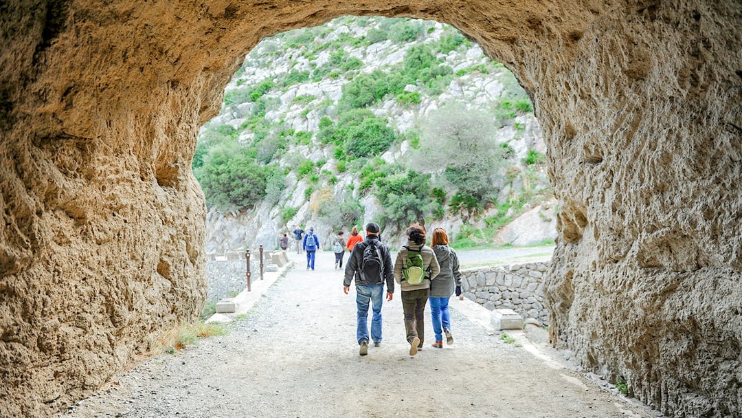 Hikers exiting Tafonis tunnel on Caminito del Rey guided tour in Spain.