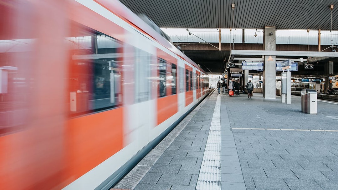 Train departing from a busy station platform with passengers nearby.