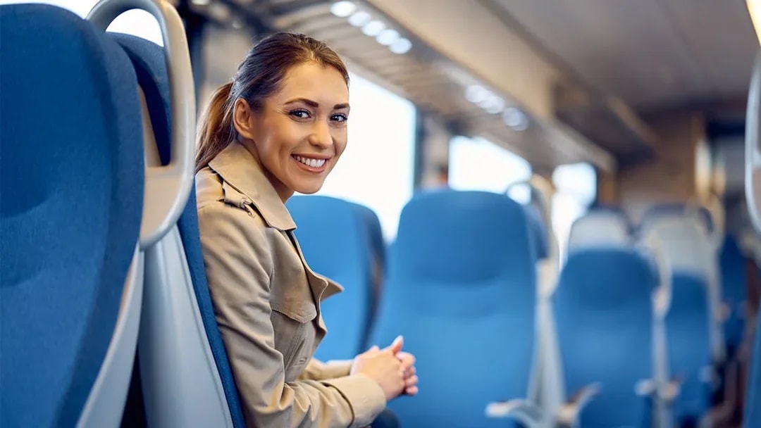 Young woman smiling while seated on a train journey.