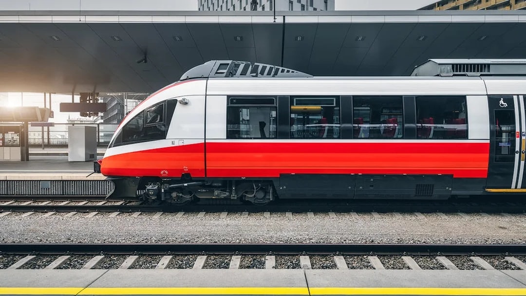 Modern red and white train at a city train station platform.