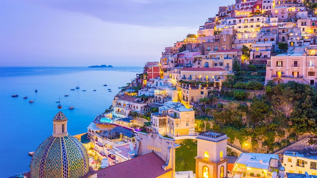 Colorful hillside buildings in Positano overlooking the sea at dusk, near the Naples to Sorrento train route.