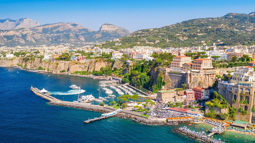 Cetara harbor on the Amalfi Coast with boats docked and colorful buildings on cliffs.