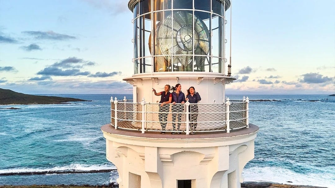Visitors on Cape Leeuwin Lighthouse balcony overlooking ocean views.