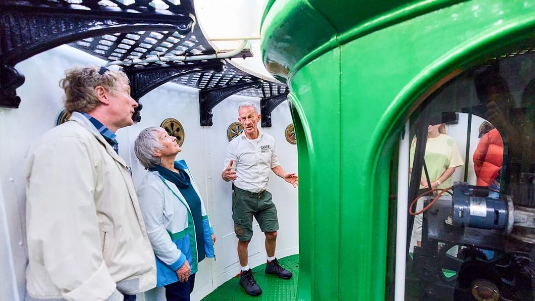 Tour guide explaining inside Cape Leeuwin Lighthouse lamp room to visitors.
