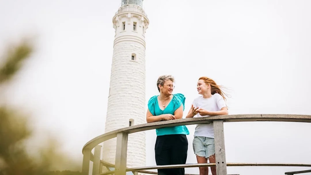 Two women on boardwalk with Cape Leeuwin Lighthouse in background.