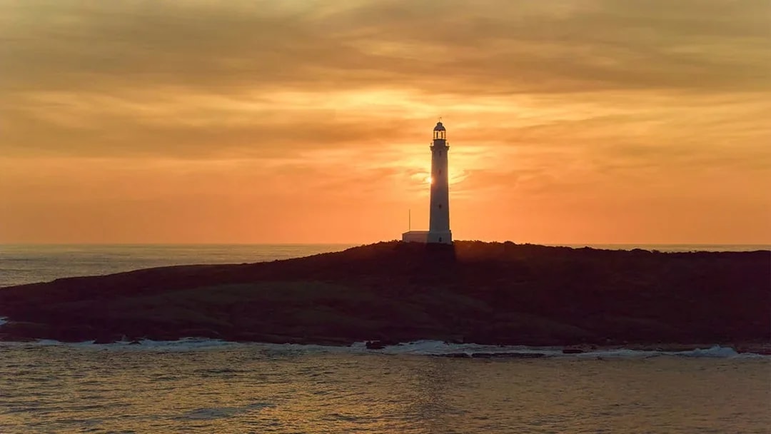 Cape Leeuwin Lighthouse silhouetted against sunset sky in Australia.