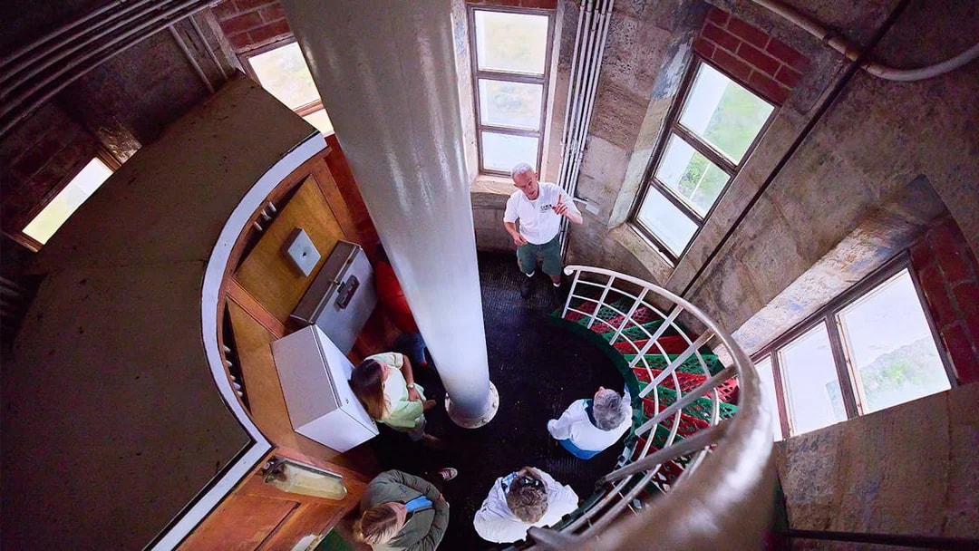 Tour group inside Cape Leeuwin Lighthouse, viewed from above on spiral stairs.
