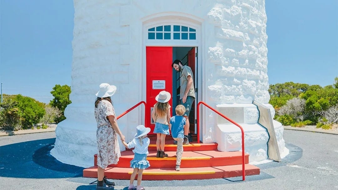 Family entering red door of Cape Naturaliste Lighthouse, "1903" above.