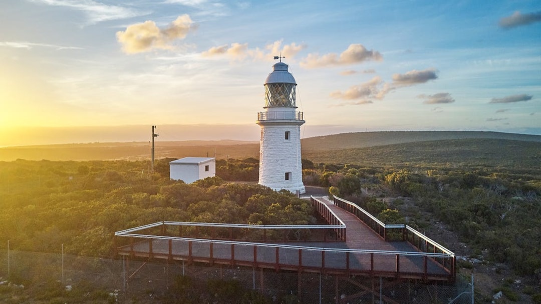 Cape Naturaliste Lighthouse at sunset with boardwalk and coastal vegetation, Western Australia.