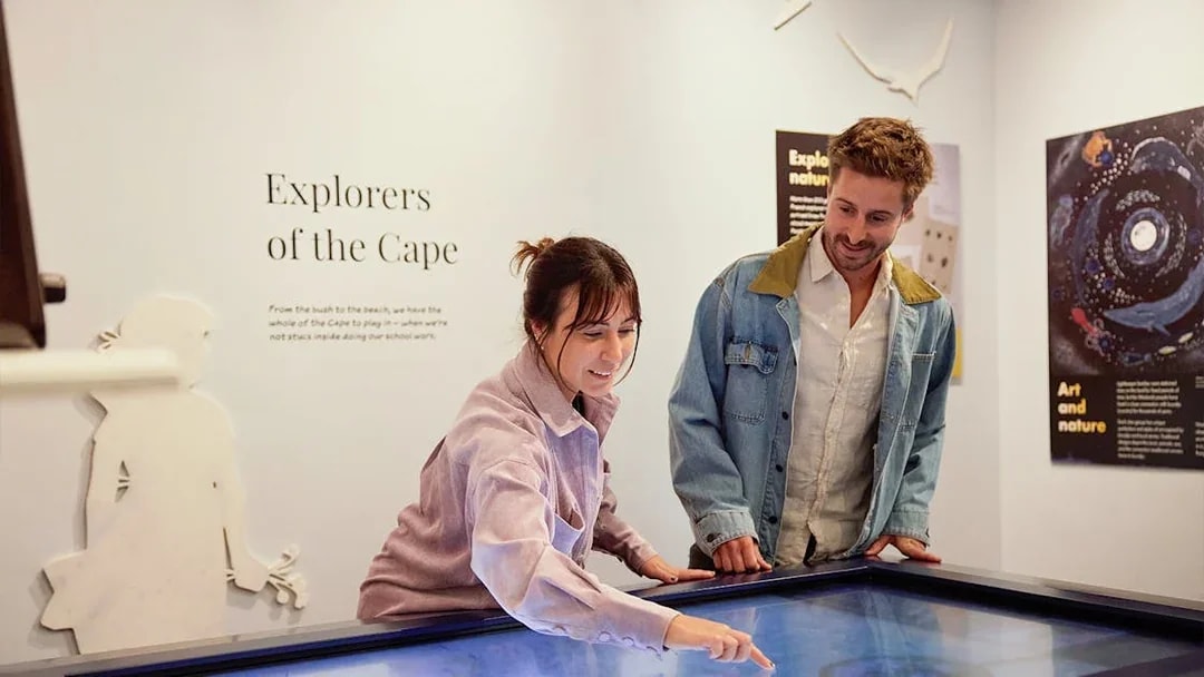 Visitors interact with "Explorers of the Cape" display at lighthouse museum.