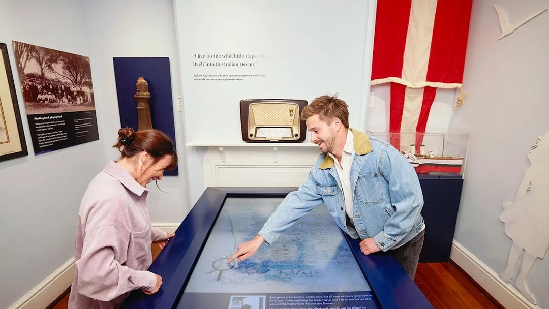 Two people engage with an interactive map display at Cape Naturaliste Lighthouse museum.