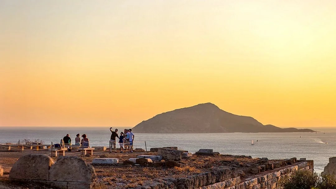 Tourists taking selfie at sunset in Archaeological Site of Sounion, Greece.