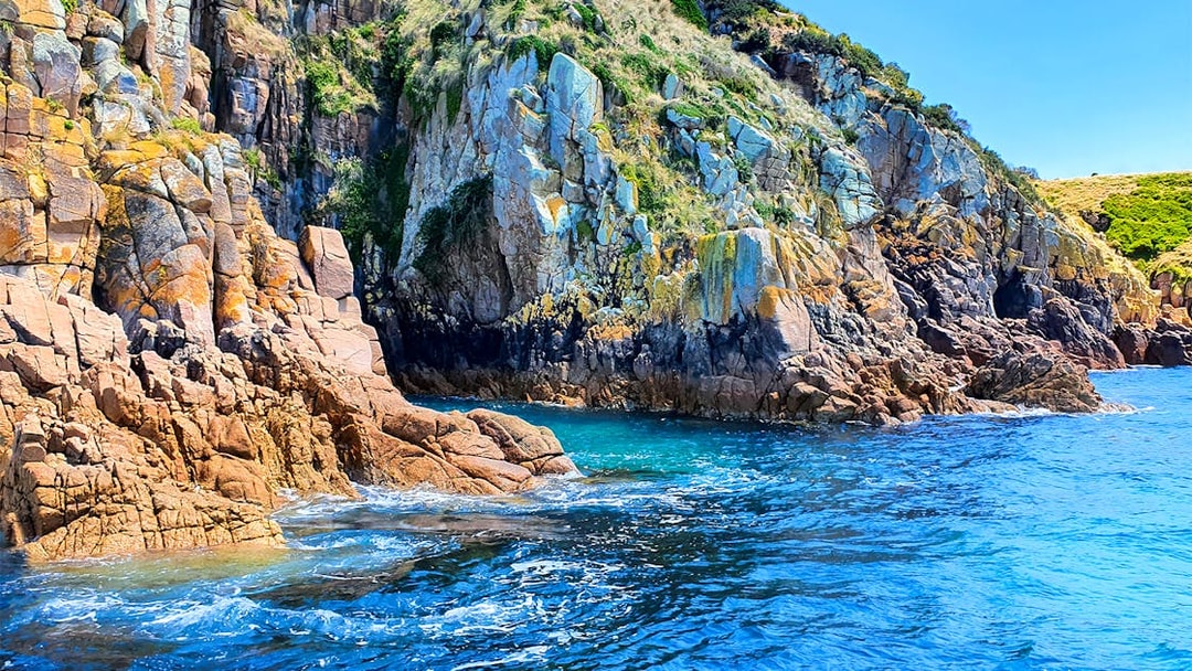 Rocky cliffs and blue ocean at Cape Woolamai, Phillip Island cruise.