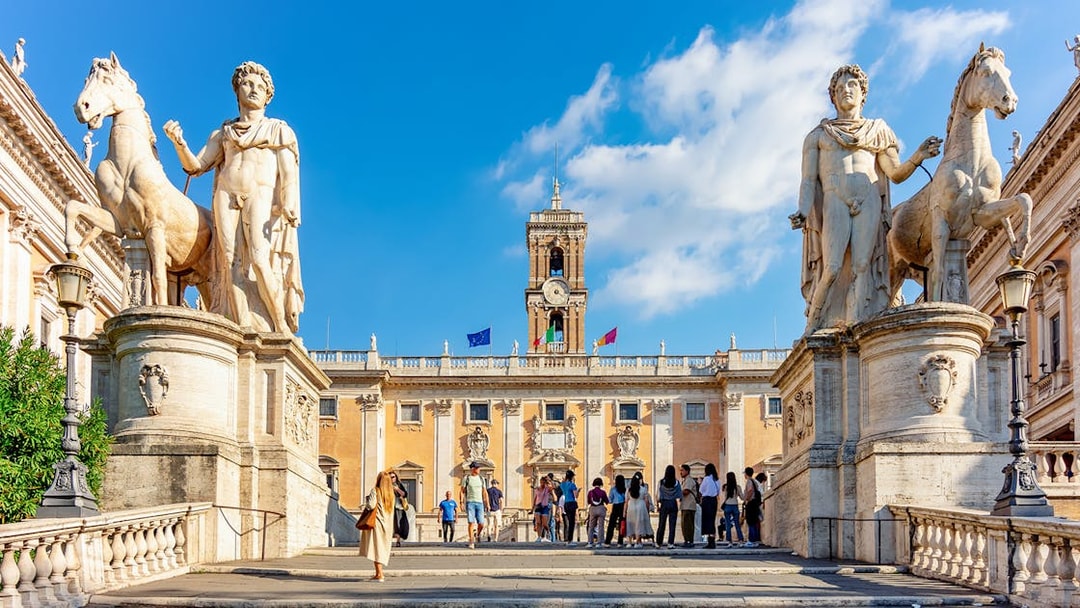 Visitors at Capitoline Museums entrance in Rome, flanked by statues of Castor and Pollux.