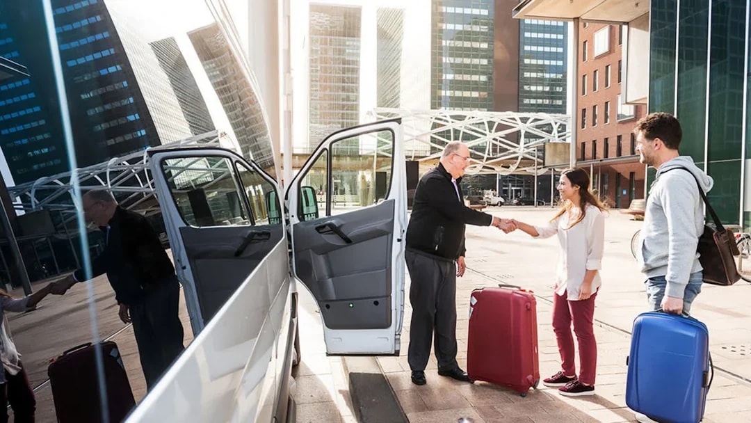 Shuttle driver greeting passengers with luggage outside Cappadocia airport.