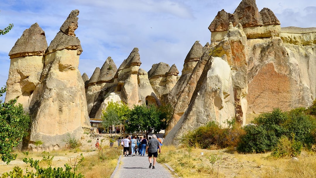 Tourists walking through rock formations at Göreme Open-Air Museum, Cappadocia.