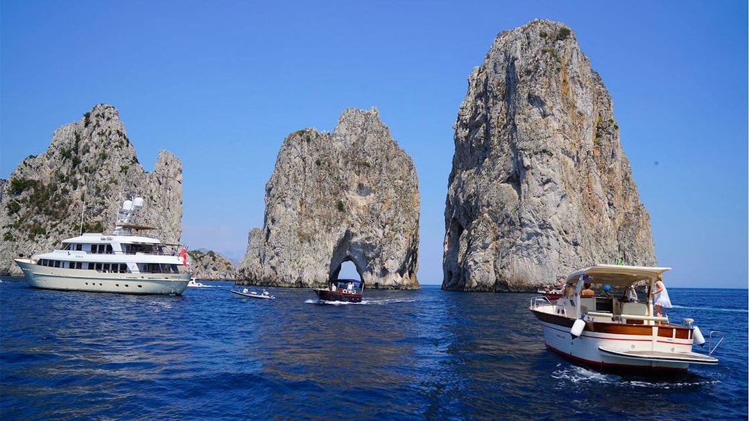 Boats near Faraglioni rock formations on Capri Island during guided tour.