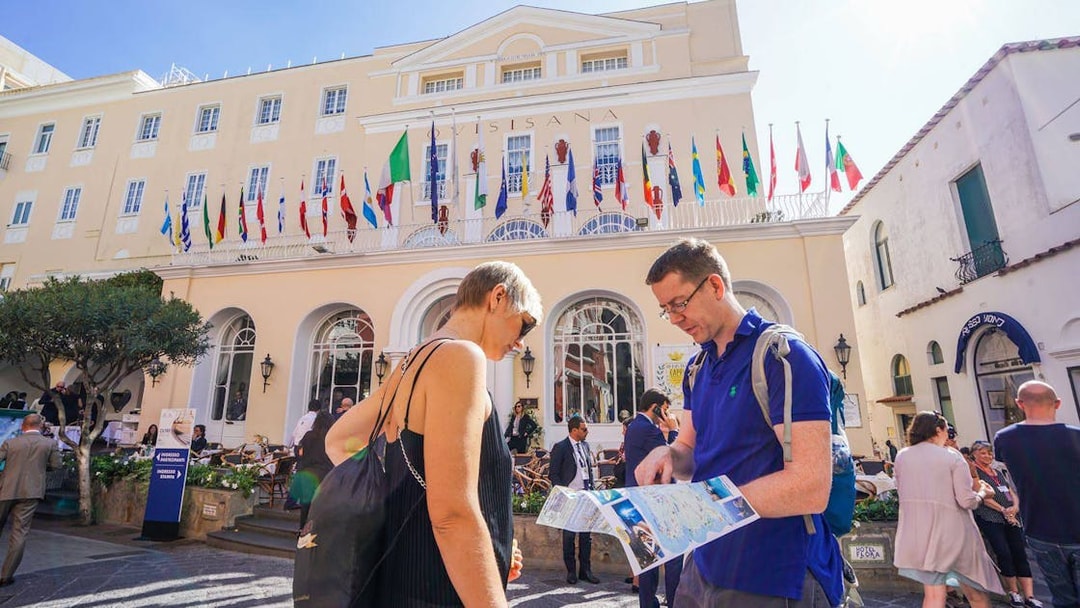 Tourists with a map in front of a building with flags on Capri Island.