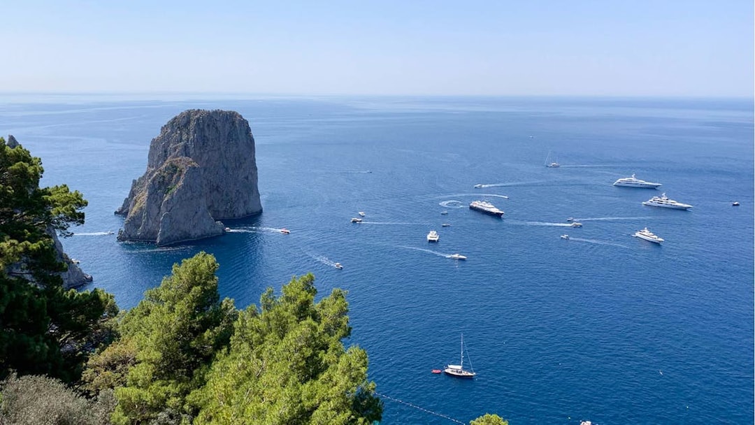 Boats sailing near Faraglioni rock formations on Capri Island, Italy.