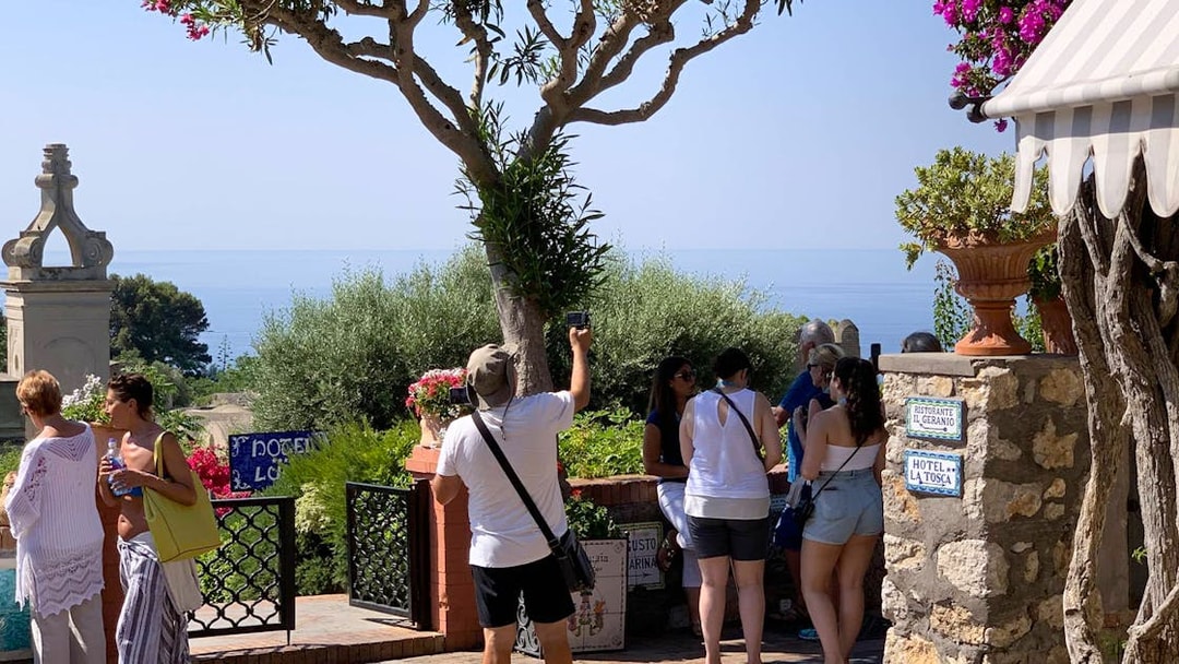 Tourists exploring Capri Island with a view of the sea and lush greenery.