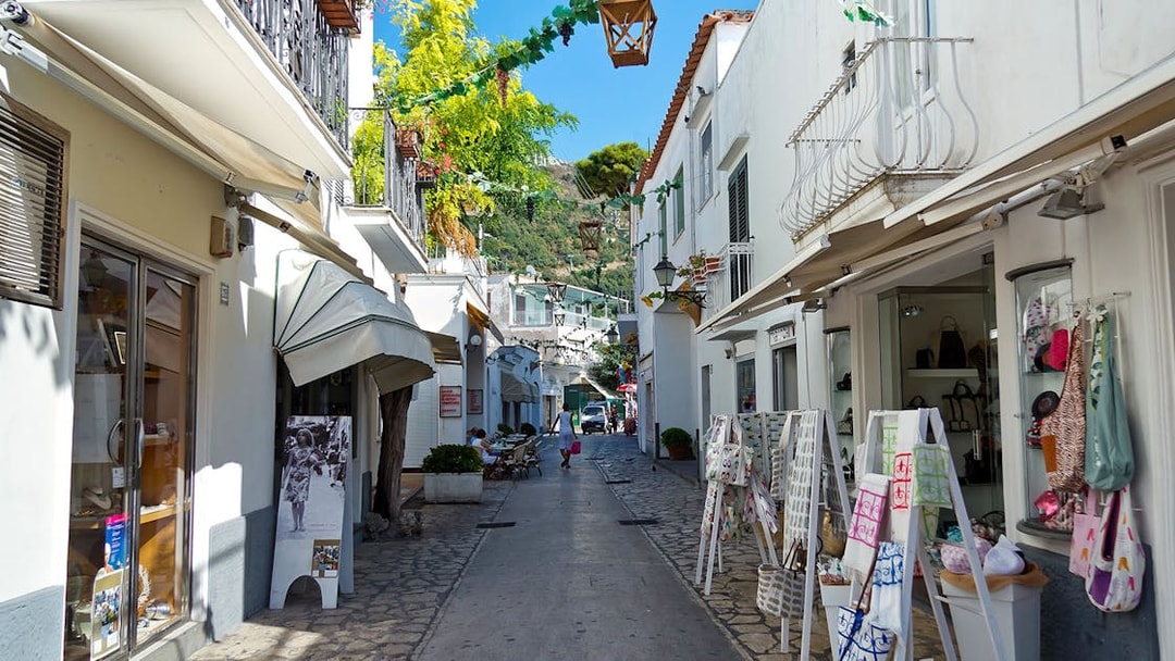 Narrow street in Capri lined with shops and outdoor displays, showcasing local charm.