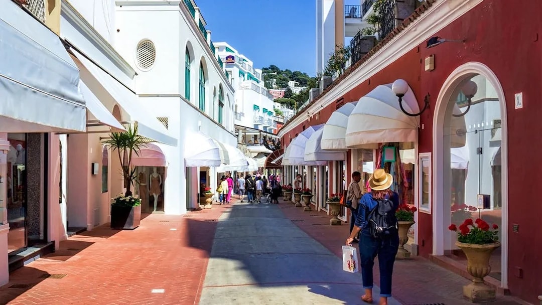 Shoppers walking through a vibrant street in Capri, Italy, lined with boutique stores.
