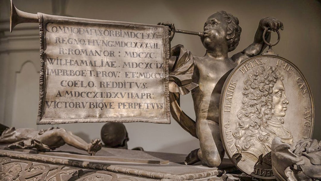 Sculpture detail inside Minoritenkirche, Vienna, featuring a cherub with a trumpet and inscribed banner.