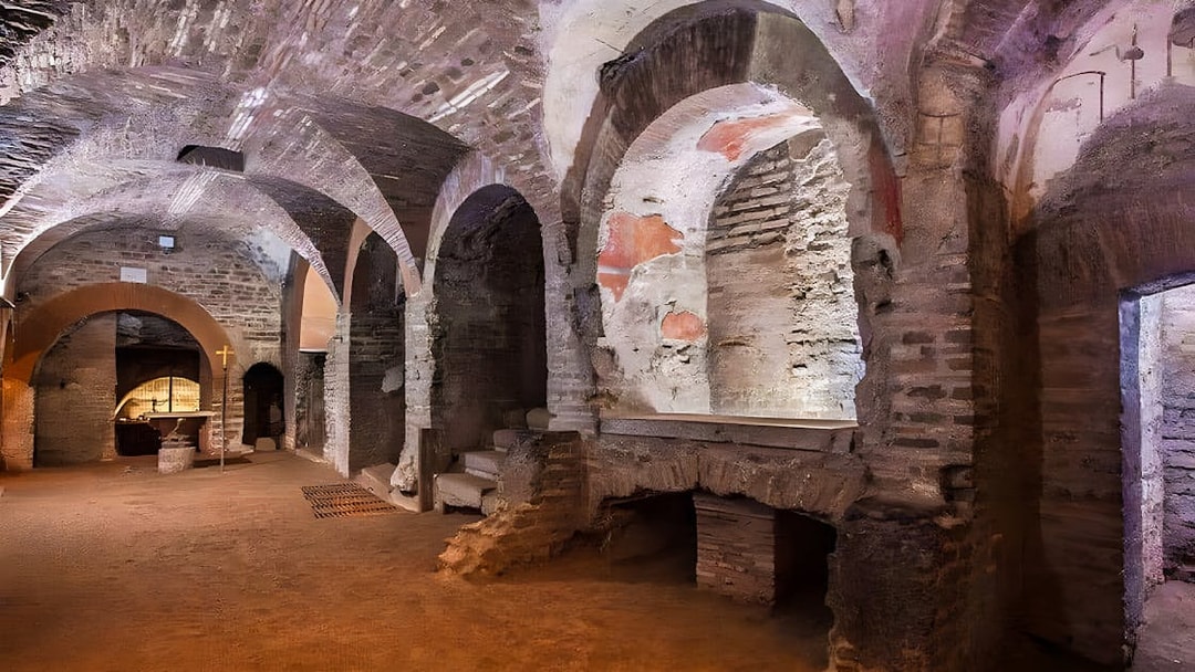 Roman Catacombs with ancient arches and altar, part of Capuchin Crypts tour.