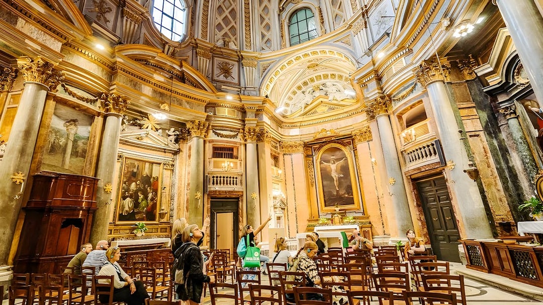 Interior of Basilica of San Nicola with visitors on a guided tour, featuring ornate architecture and religious artwork.
