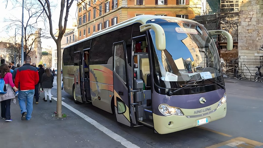 Tourists boarding an AC coach vehicle on a city street.