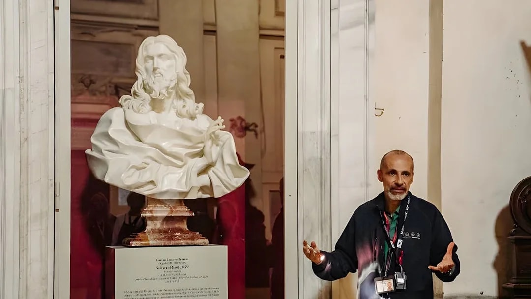 Guide explaining a marble bust in the Basilica of San Nicola during a Roman Catacombs tour.