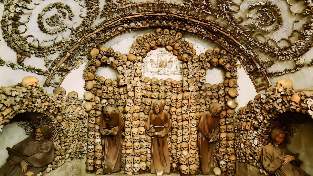 Crypt of the Capuchin Friars in Rome, featuring walls adorned with human skulls and bones.