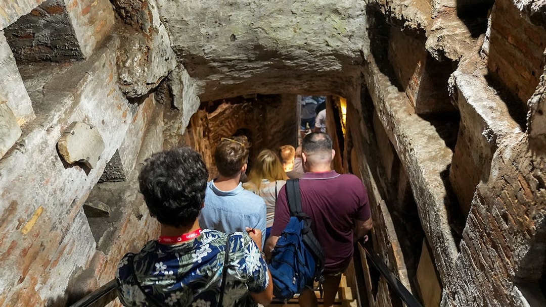 Visitors descending stairs into Capuchin Crypt with guide in Rome.
