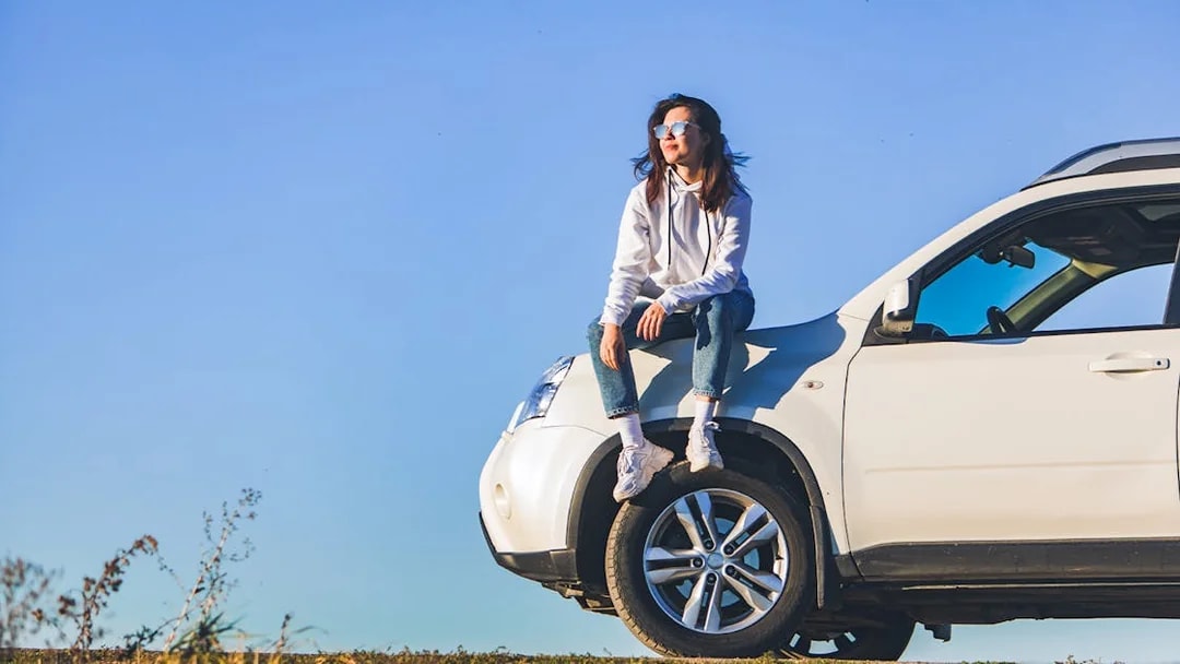 Person sitting on a white SUV under a clear blue sky in Langkawi.