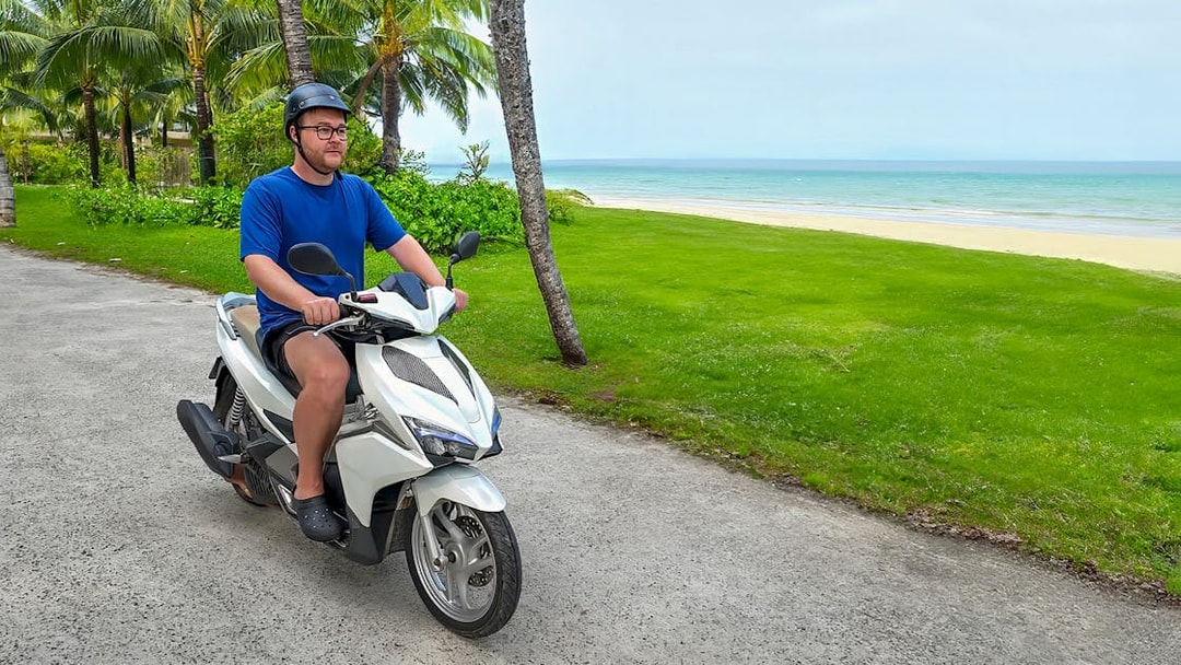 Man riding a motorbike along a coastal path in Langkawi.
