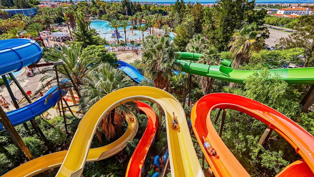 Colorful water slides at Caribe Aquatic Park with lush greenery and pools in the background.
