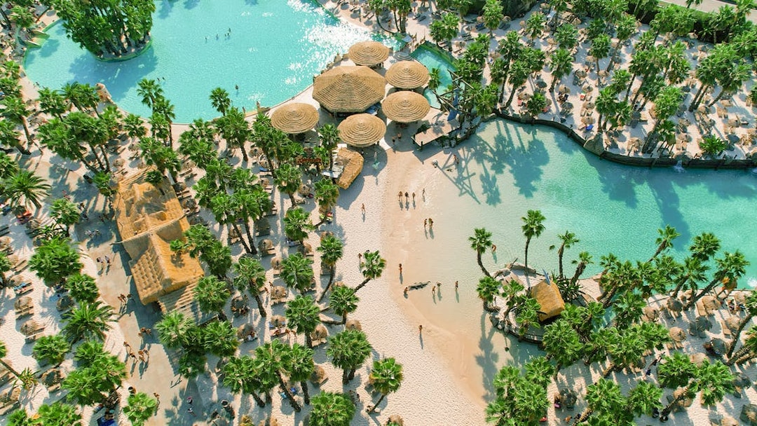 Aerial view of Caribe Bay with palm trees, sandy beaches, and turquoise pools.