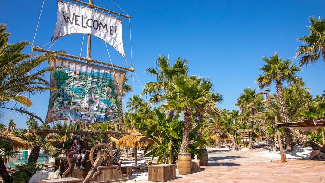 Caribe Bay entrance with pirate-themed decor and palm trees under a clear blue sky.