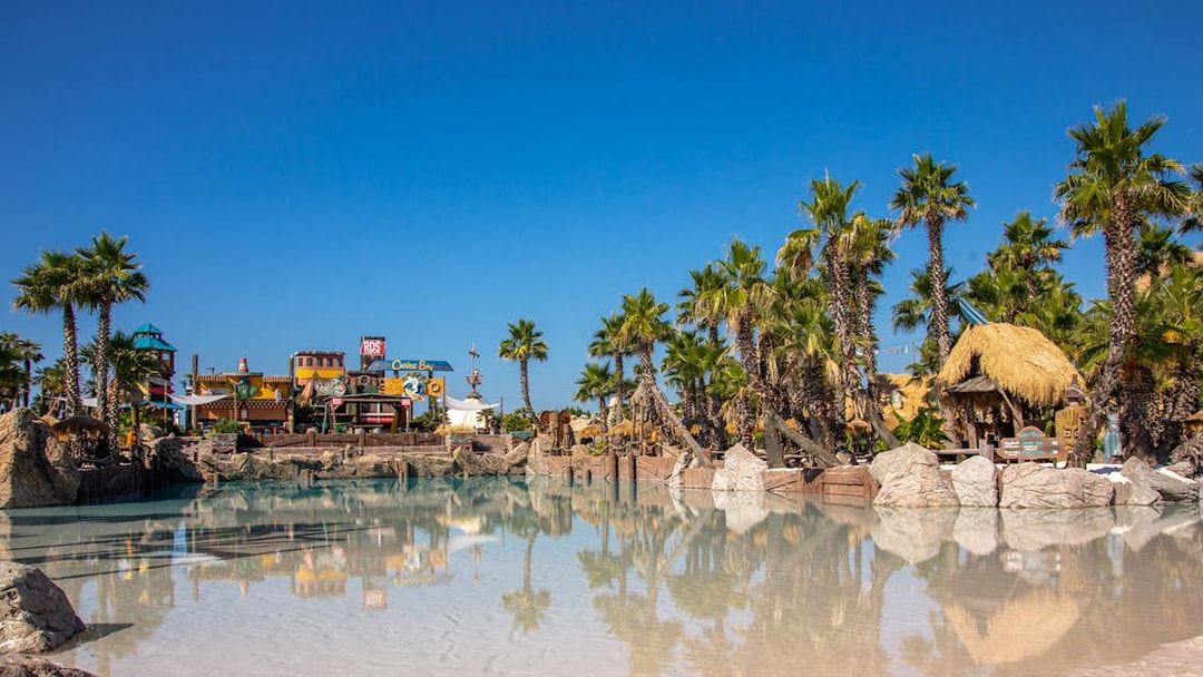 Caribe Bay water park entrance with palm trees and themed structures.