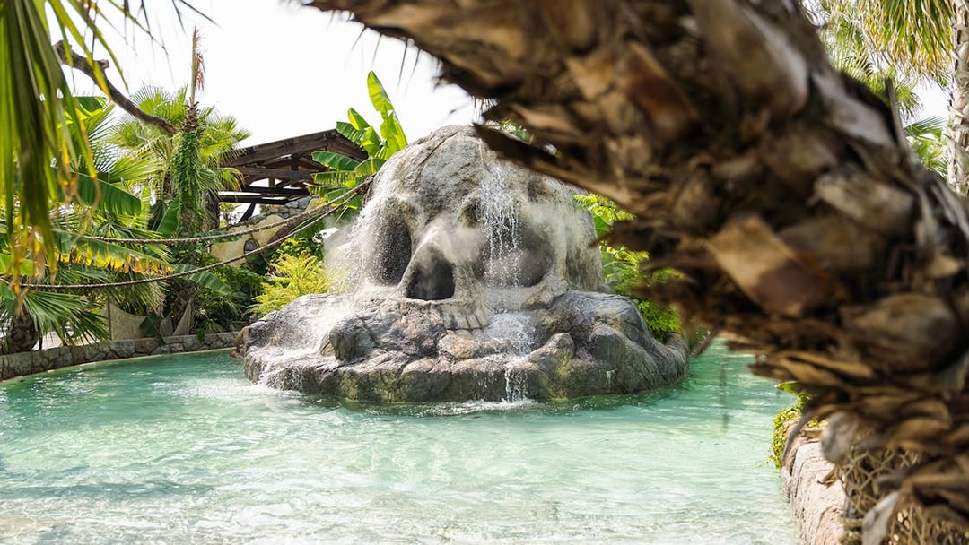 Skull-shaped rock waterfall at Caribe Bay water park entrance.