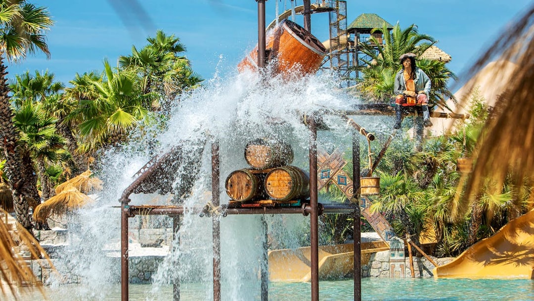 Water splash feature at Caribe Bay with palm trees and slides in the background.