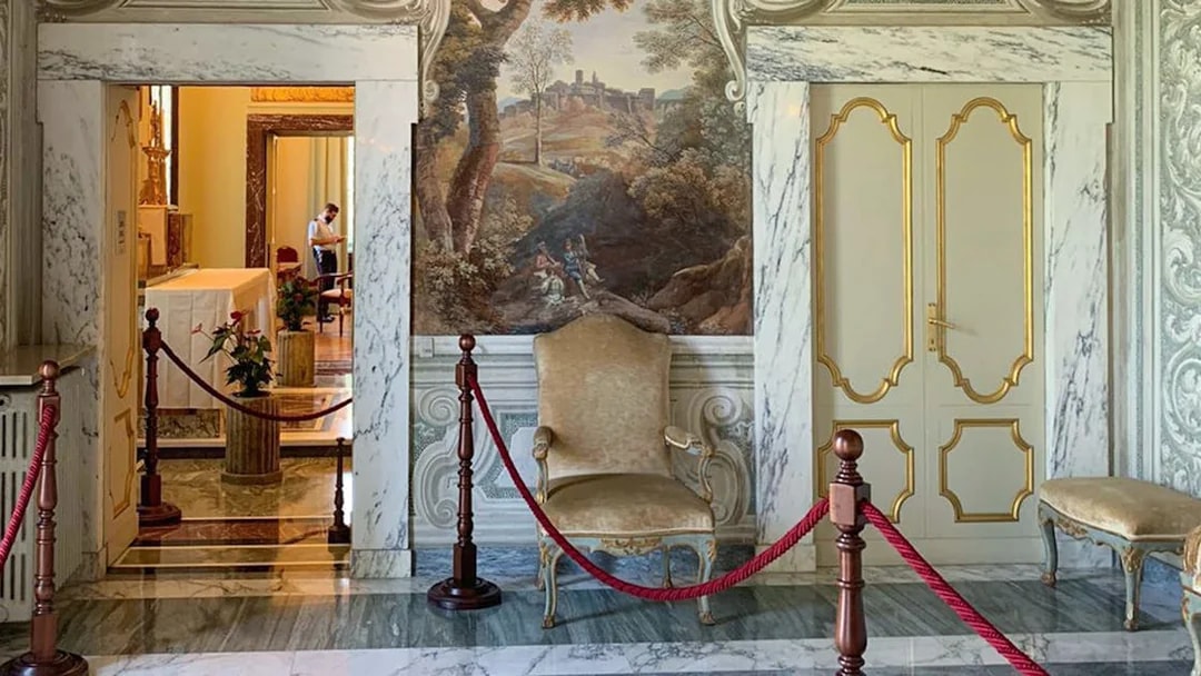Elegant interior of Castle Gandolfo with ornate chair and mural.