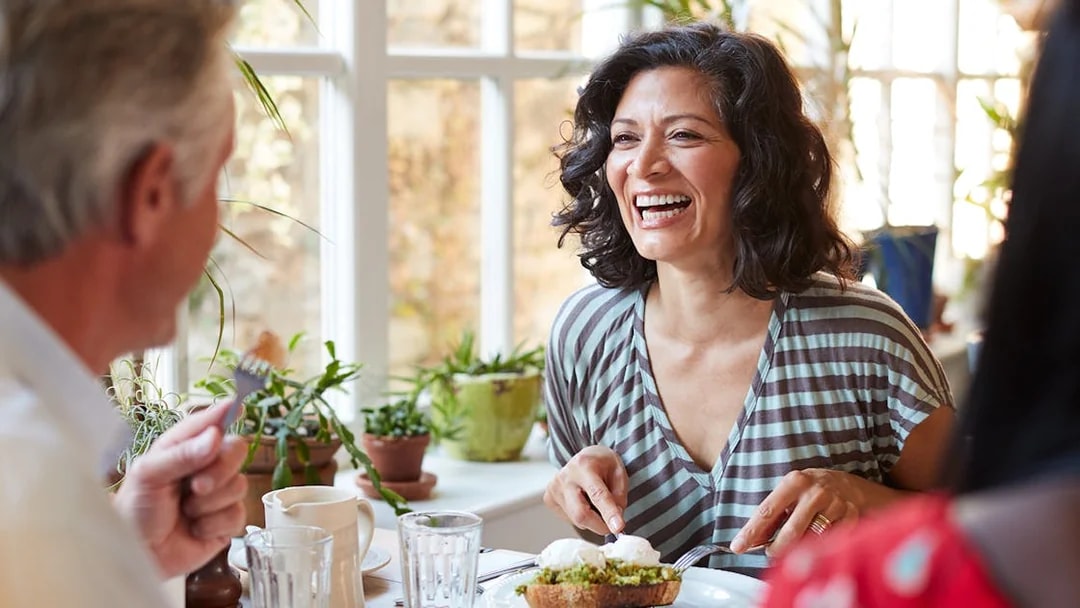 Woman enjoying brunch with friends in a bright cafe.